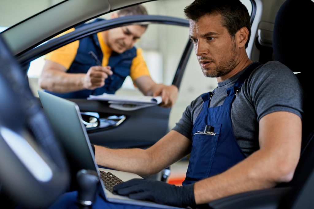 A mechanic running diagnostics on an idling commercial fleet vehicles
